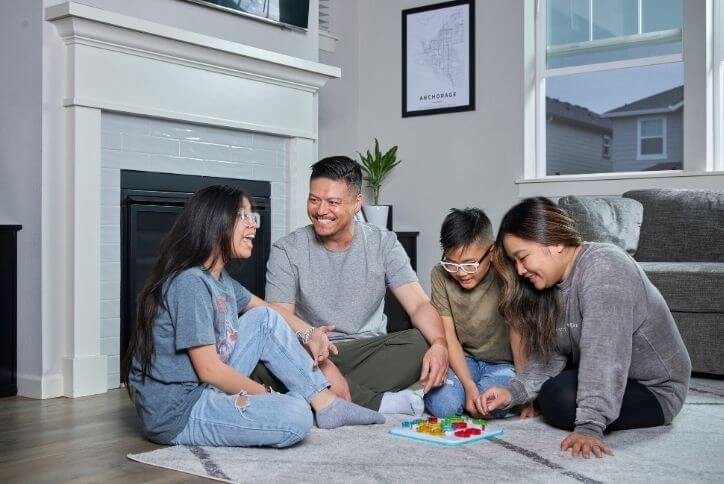 A family sits in a circle on the floor playing a board game.