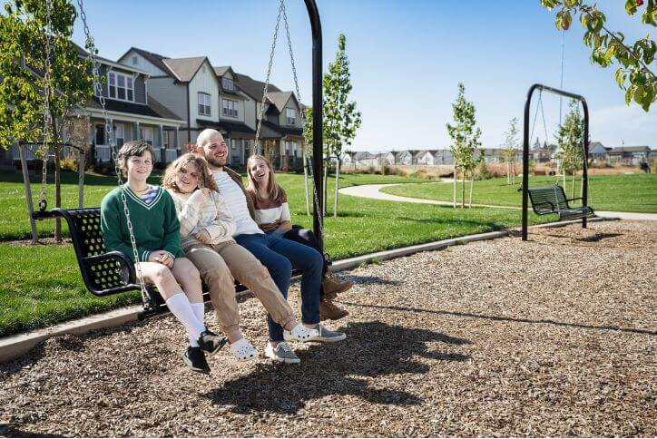 A laughing young family crowds onto a bench swing in Hillsboro’s Tamarack Park.