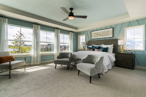 A bedroom decorated in pale sage green in a home by David Weekley at Reed’s Crossing.