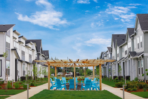 A firepit surrounded by Adirondack chairs sits amongst new homes for sale in Reed’s Crossing.