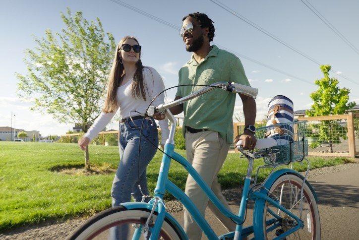 A young couple walks with a bike near Reed’s Crossing Community Garden.