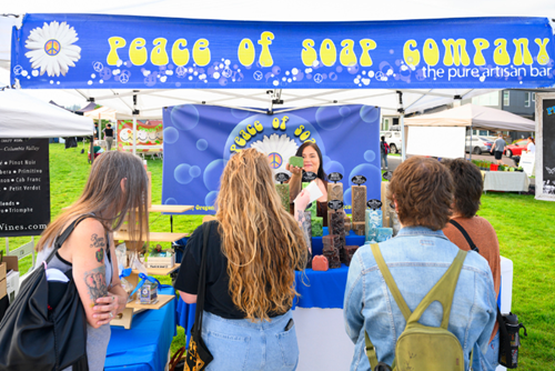A vendor hands aromatherapy soaps to customers at Hillsboro Farmers’ Market at Reed’s Crossing.