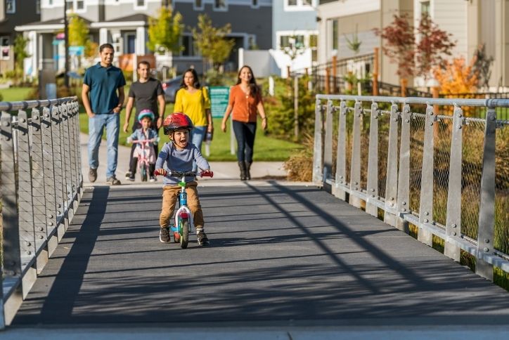 Alt text: Two families walking along the paths at Reed’s Crossing.