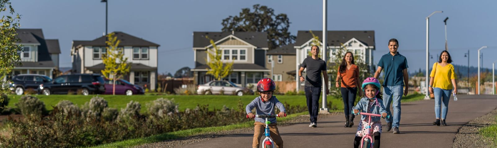 Children riding bikes on a path with family Reeds Crossing Community Hillsboro OR