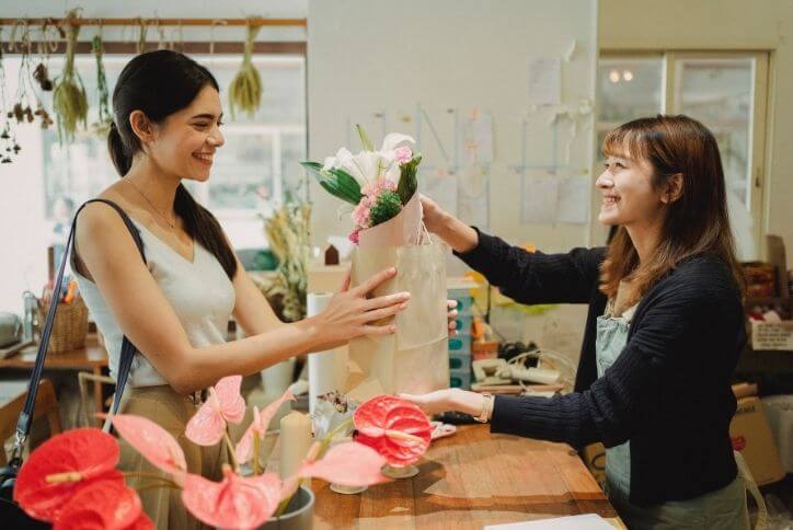 A florist hands a bouquet of flowers to a customer.