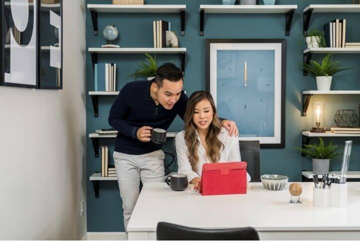 A young couple using a laptop in a home office.