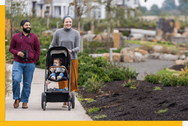 Couple walking with baby in stroller at Reed's Crossing Community