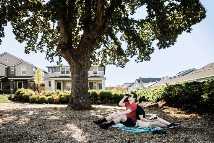 A man and woman sit on a blanket in Hillsboro’s Oak Grove Park, birdwatching and reading.