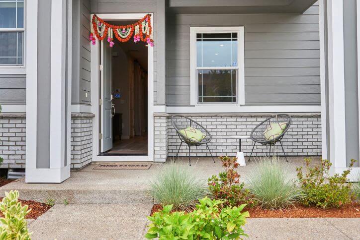 A new construction home at Reed’s Crossing features a cozy front patio with two gray Acapulco chairs.