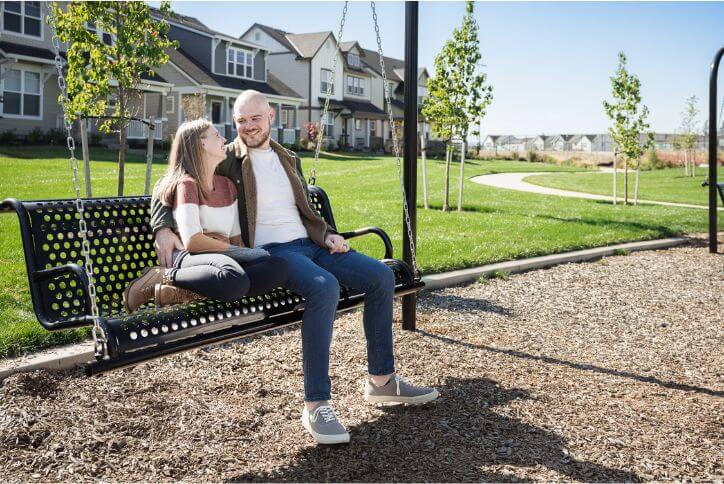 A man and a woman cuddle on a bench swing in South Hillsboro’s Tamarack Park.
