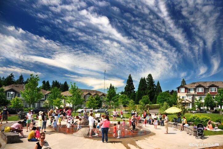 A group of about 30 people enjoy one of Hillsboro’s spraygrounds, a playground equipped with large fountains to play in.