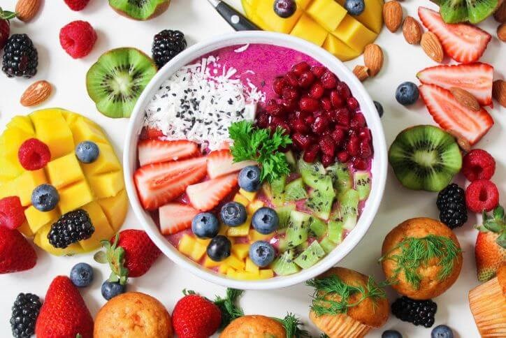 A colorful smoothie bowl topped with strawberries, blueberries, kiwi, and coconut.