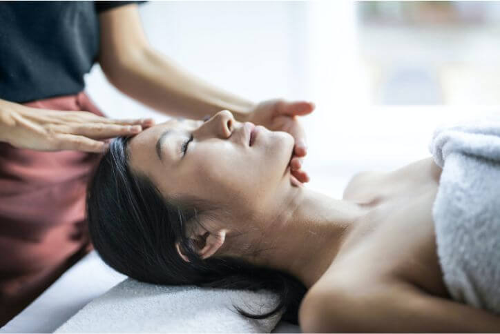 Selective focus photo of a woman getting a head massage.