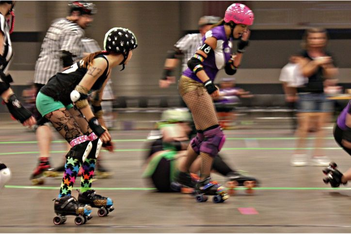 Selective focus shot of a group of roller derby skaters as they fly by the camera.