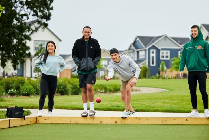 Four young adults play bocce ball at Tamarack Park in Hillsboro, OR.