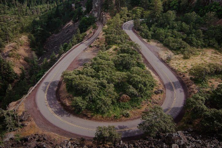 A road loops through green forest on a scenic highway in Oregon.