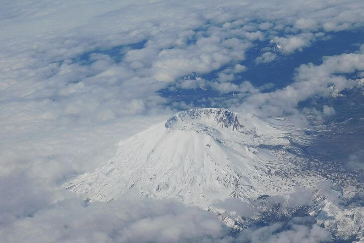 A shot from above Mount St. Helens shows the crater peeking through clouds.