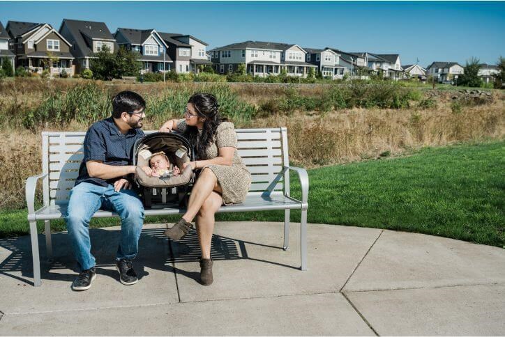 A couple sits on a bench with a sleeping baby in Hillsboro’s Dobbin Park.