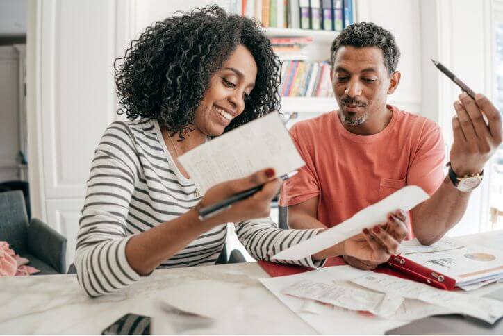 A couple in the kitchen with receipts and a financial planning notebook.