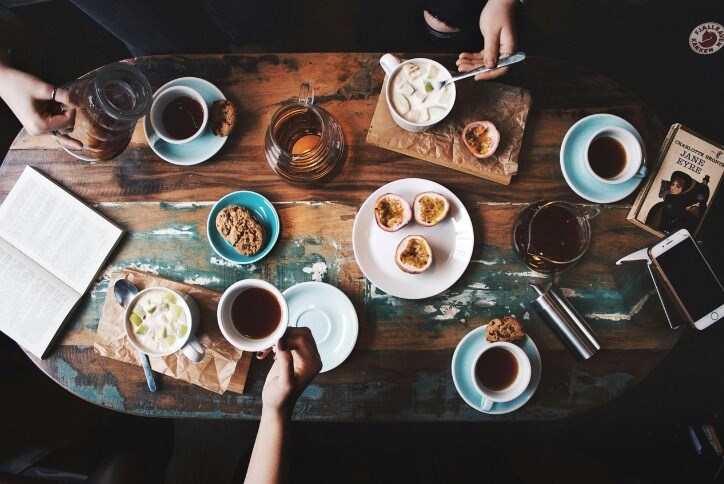 Above-the-table view of two people having tea and cookies in a coffee shop.