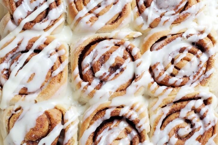 A tray of cinnamon rolls with white icing.