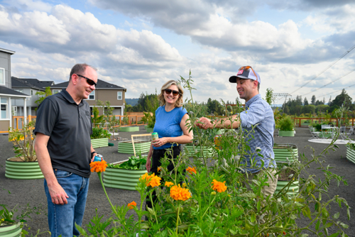 Two men and a woman admire a garden plot in the Reed’s Crossing Community Garden.