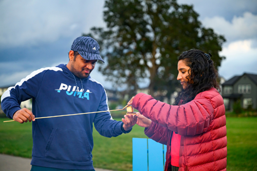 A couple prepares smores together during firepit night in Tamarack Park at Reed’s Crossing.