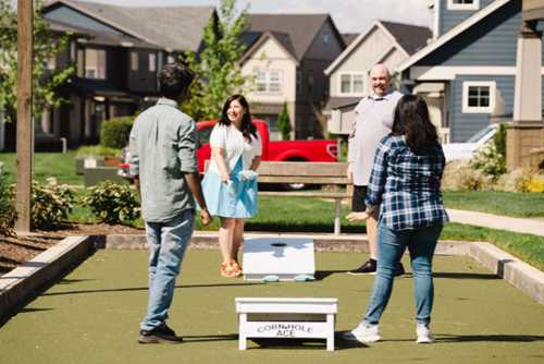 Two couples enjoy a game of cornhole in Hillsboro, Oregon’s Reed’s Crossing community.