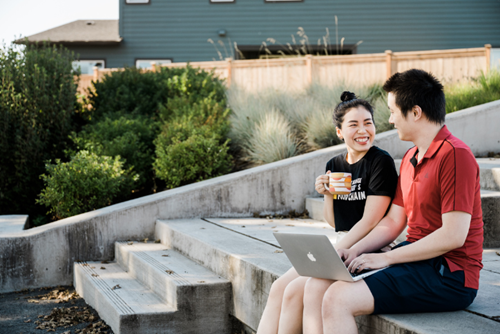 A young couple uses a laptop in the middle of Oak Grove Park in Reed’s Crossing.