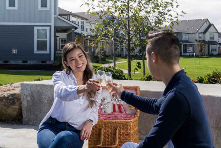 A young couple raises glasses of wine at a picnic on a sunny day in Reed's Crossing.