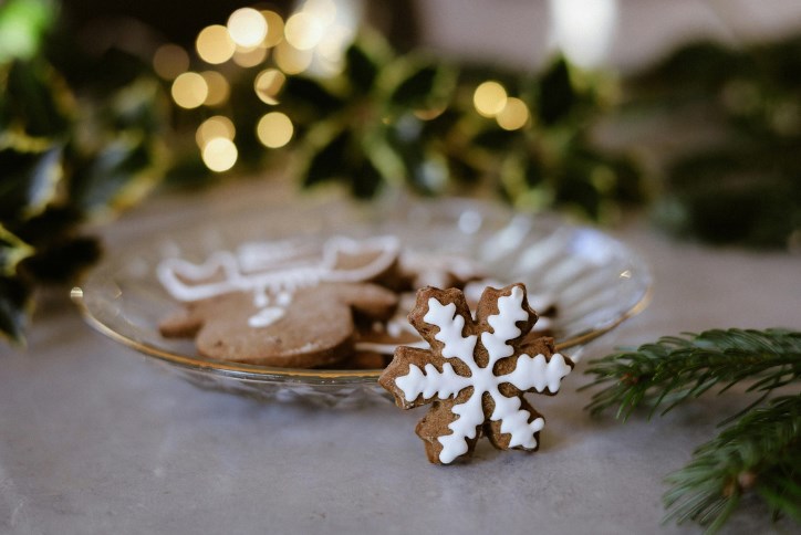 A plate of holiday cookies surrounded by Christmas greens and white lights.