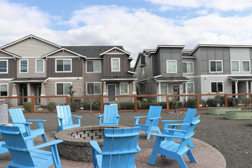 A community space with a firepit and teal Adirondack chairs abuts homes for sale at Reed’s Crossing in Hillsboro, Oregon.