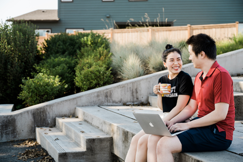 A man and woman sit on the tiered benches in Oak Grove Park at Reed’s Crossing.