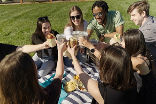 A group of young people raises beverages to say cheers during a picnic in Reed’s Crossing Park.