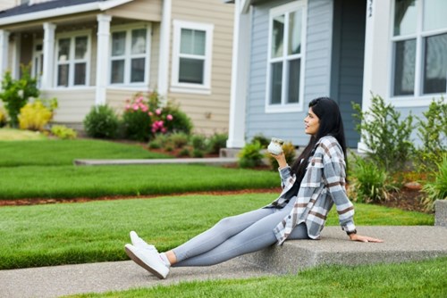 A young woman relaxes with a beverage on the steps outside her home in Hillsboro, Oregon.