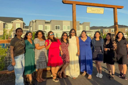 A group of friends pose in front of the Reed’s Crossing Community Garden.