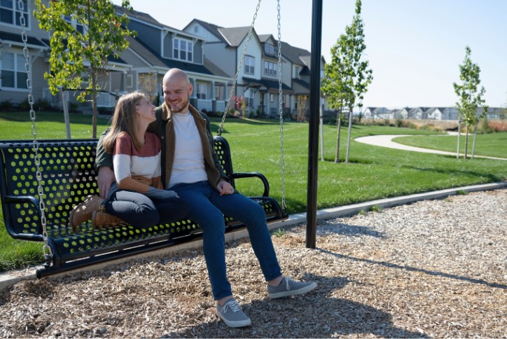 A man and woman cuddle on a bench swing at Tamarack Park in Reed’s Crossing.