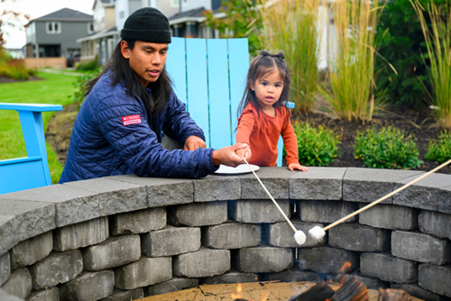 A father and young daughter roast marshmallows at a fire pit in Reed’s Crossing.