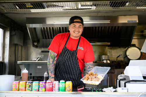 A local food truck vendor shows off their signature dish at Food Truck Night in Reed’s Crossing.