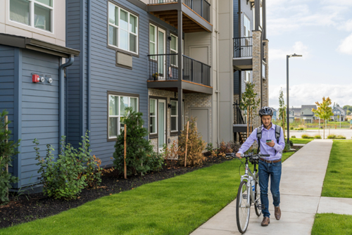 A man walks a bicycle through the Zera Apartments complex in Hillsboro, Oregon.