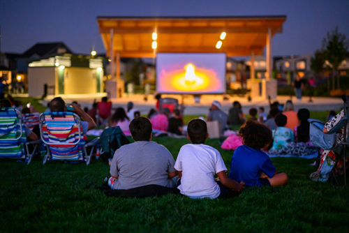 Families gather in Reed’s Crossing Park for a movie at dusk.