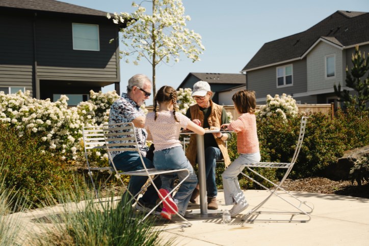 A family plays a board game in Reed’s Crossing Community Garden.