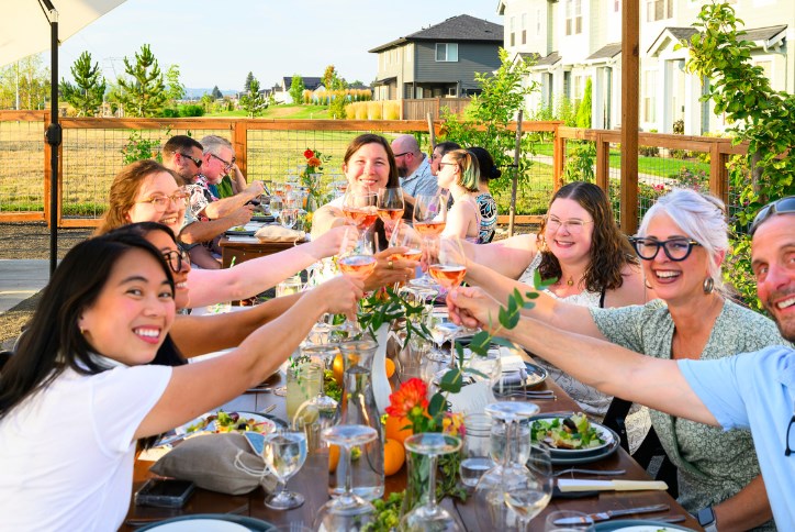 A group of neighbors raises their glasses at a community garden event in Reed’s Crossing.