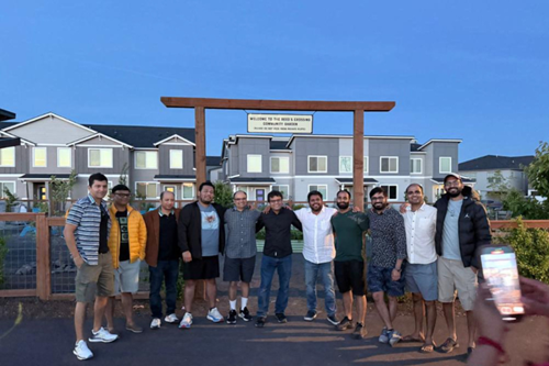 A group of friends pose in front of Reed’s Crossing Community Garden.