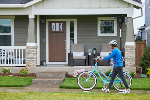 A man walks a bicycle in front of a home at Reed’s Crossing, known for its bike-friendly design.