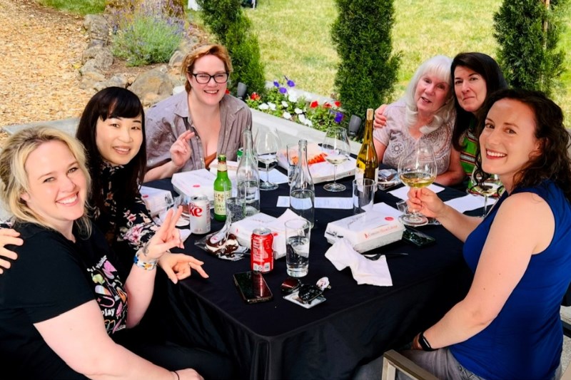 A family gathers around a table for a meal outdoors.