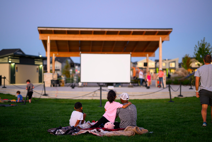 Families gather in Reed’s Crossing Park for a movie at dusk in the amphitheater.
